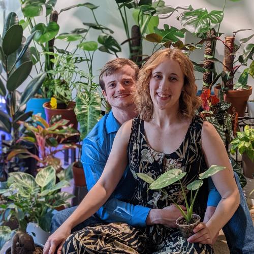 Co-founders Nolan and Kayla Gajdascz of Mental Houseplants sitting together with their personal indoor plant collection.